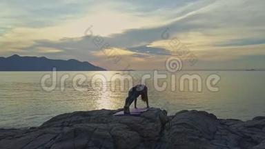 在海面上日出时，观影女孩手持瑜伽姿势